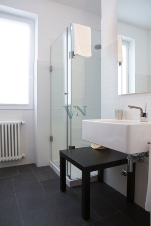Bathroom features a glass-enclosed shower, white sink, and black countertop.