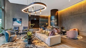 A modern lobby with a sofa, chairs, and a unique circular light fixture.
