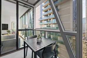 A modern apartment with a balcony, large windows, and a view of other buildings. - Opulent Suite at Westside Place (Melbourne)