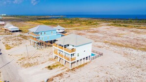 Een strandpand met twee blauwe gebouwen, waarvan er een balkon heeft en de ander een zwembad.