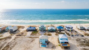 A beachfront property with multiple houses, a swimming pool, and a pier.