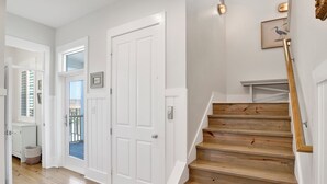 Een trap met houten treden en witte muren, leidend naar een plateau met een ingelijste foto.