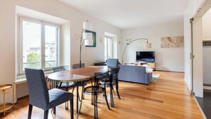 A modern living room with a dining area, large windows, a flat-screen TV, and a sofa. - Tricolore · (Piazza Tricolore) Metro Blu Duomo a 10 minuti (Milano)