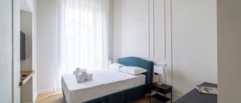 Ein ordentlich eingerichtetes Schlafzimmer mit Bett, Nachttisch und einem kleinen Tisch mit einer Zeitschrift.