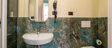 A bathroom with a marble wall, a sink, a bidet, and a toilet.
