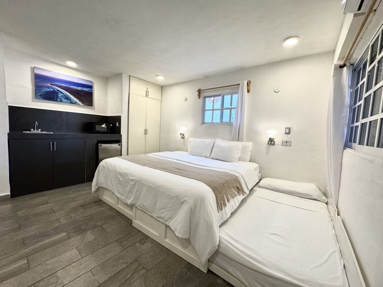 Une chambre à coucher avec un lit, un petit bureau, une fenêtre et un tableau accroché au mur.