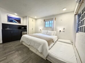 A bedroom with a bed, a small desk, a window, and a painting on the wall. - La Perle Noire | AB - Terasse et Piscine (San Miguel de Cozumel)