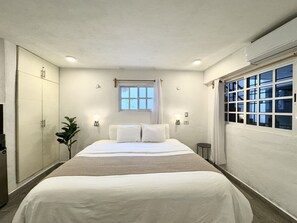A bedroom with a bed, a window with curtains, a plant, and a wardrobe. - La Perle Noire | AB - Terasse et Piscine (San Miguel de Cozumel)