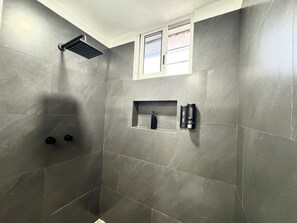 A shower area with a built-in rain showerhead, a small window, and a shelf with toiletries. - La Perle Noire | AB - Terasse et Piscine (San Miguel de Cozumel)