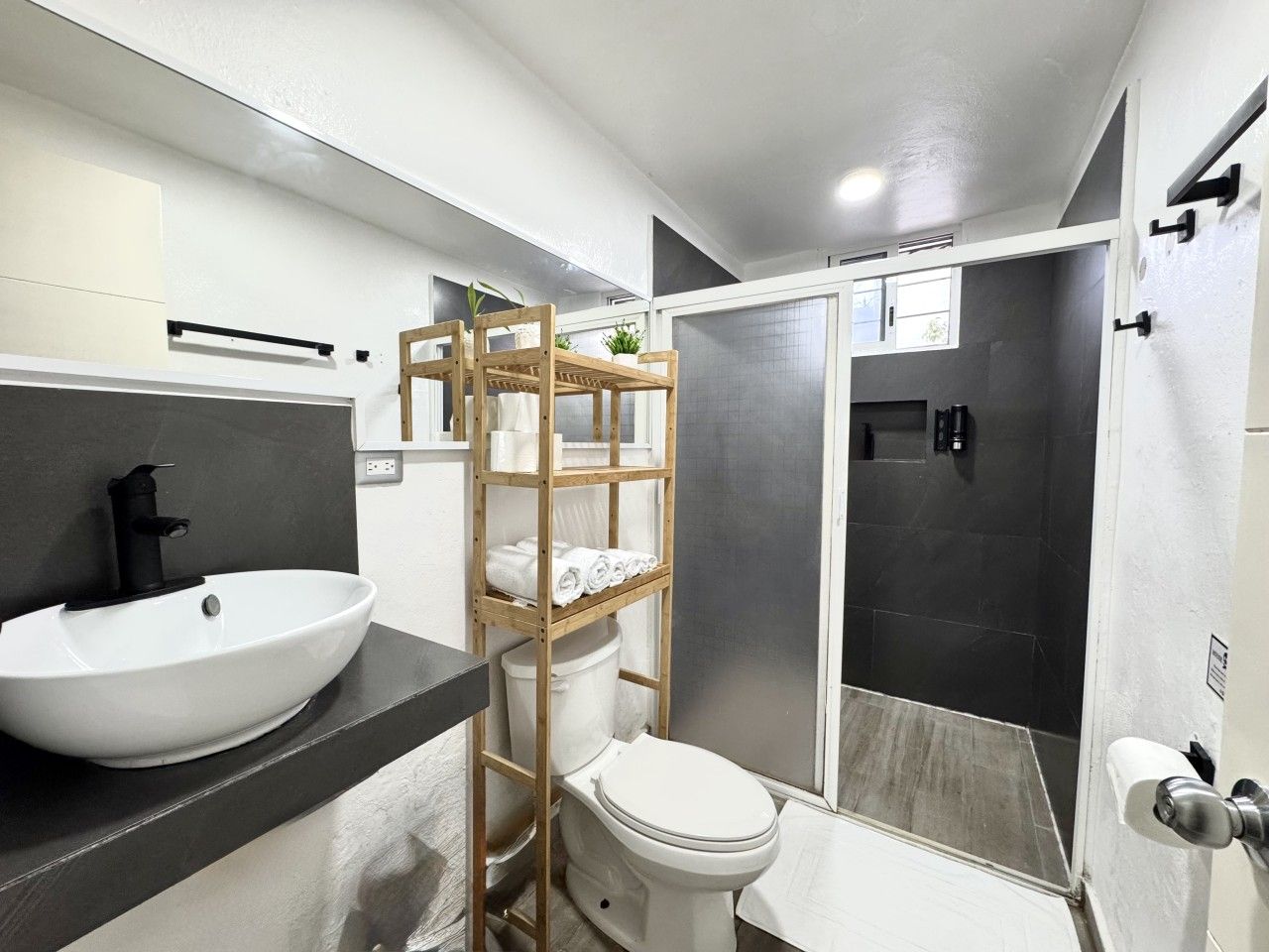 Une salle de bain moderne avec un lavabo, des toilettes et une zone de douche, le tout de couleur blanche.