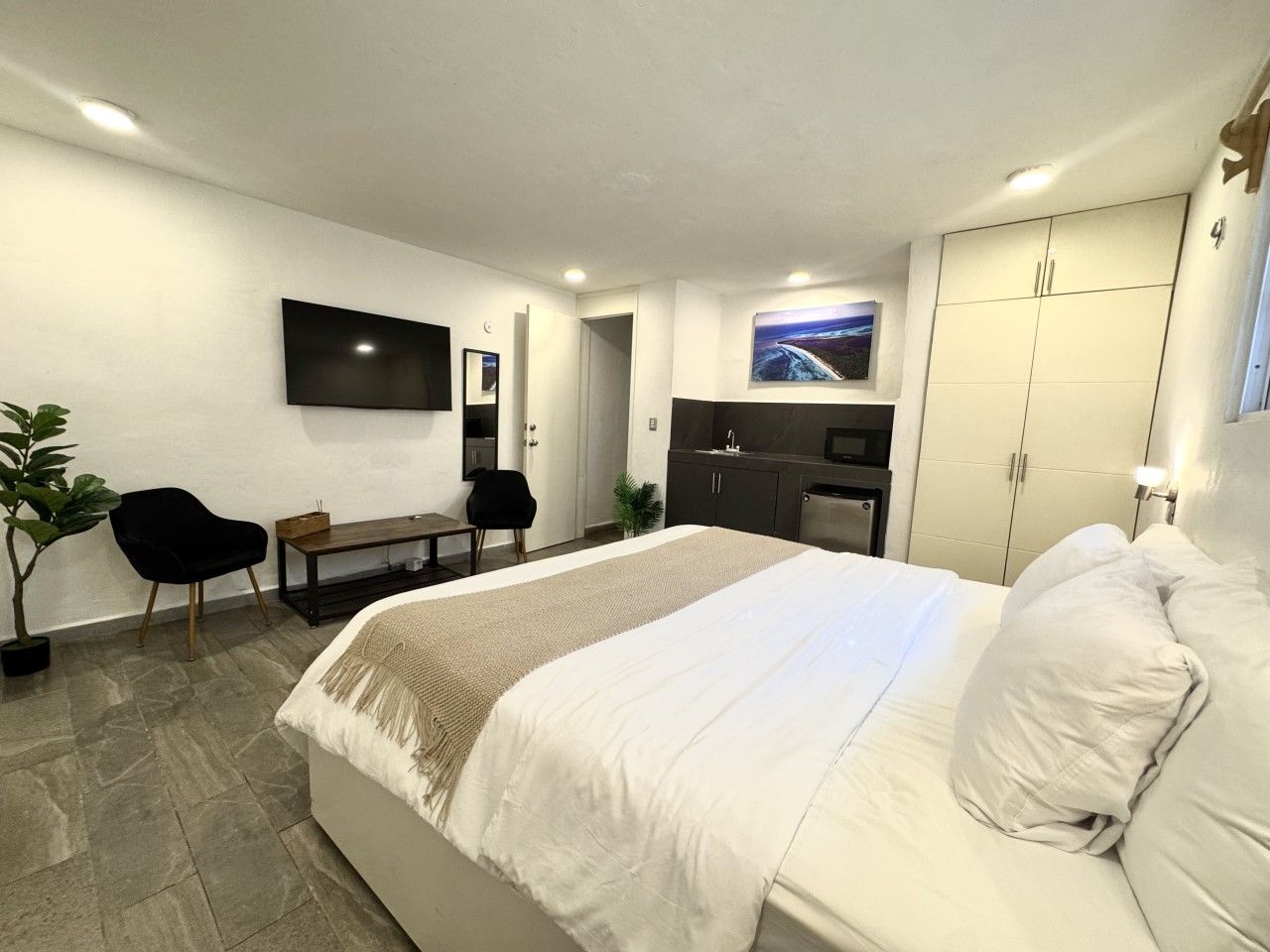 Une chambre d’hôtel moderne équipée d’un lit, d’une télévision, d’un bureau et d’une kitchenette.
