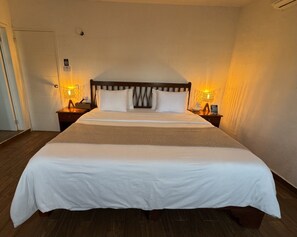 A standard hotel room with a large bed, two bedside tables, and a door.