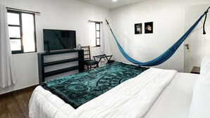 Un dormitorio con cama, escritorio, silla, televisión y una hamaca.