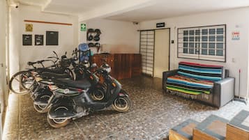 Ein Zimmer mit gefliestem Boden, einer Couch, einem Fahrrad und einem Motorrad.