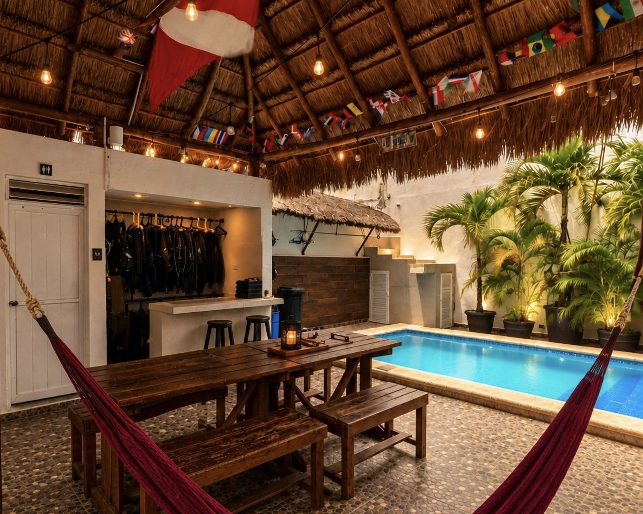 Un espace aménagé au bord de la piscine, avec une table et des bancs en bois, un toit de chaume et une piscine.