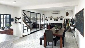 Een ruime woonkamer met een eettafel, stoelen en een trap naar een andere kamer.