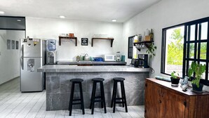 Een moderne keuken met een marmeren eiland, barstoelen, een koelkast, een magnetron en een houten kast met planten.