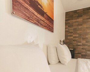 Una habitación de hotel con una cama, almohadas, un cuadro colgado en la pared y un revestimiento de pared de madera.