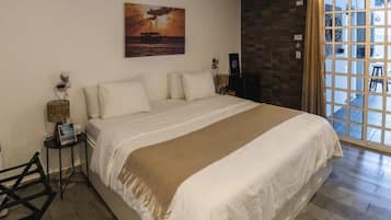 Une chambre à coucher avec un grand lit, un tableau au mur, une fenêtre avec des rideaux et une table de chevet avec une lampe.