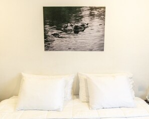 A bed with white bedding and pillows, a framed picture above it, and a plain wall. - La Perle Noire | HM - Terasse et Piscine (San Miguel de Cozumel)