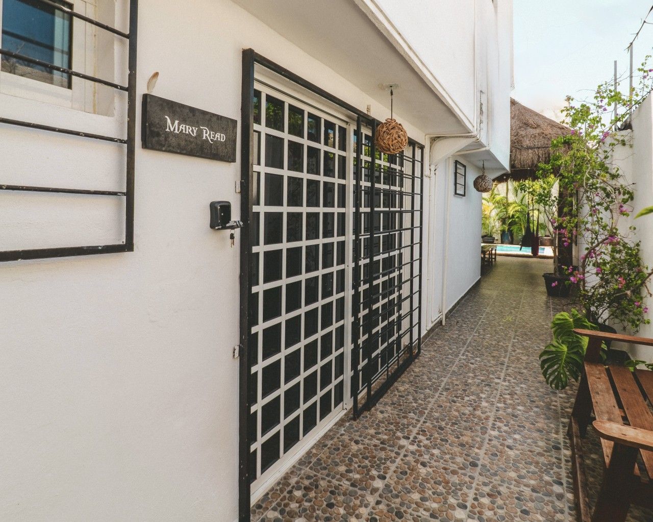 Um beco estreito com piso de azulejos, um portão de metal e um banco de madeira.