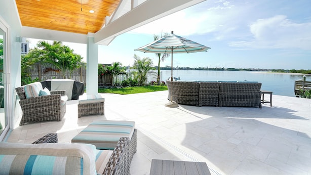 A covered patio with wicker furniture, a ceiling fan, and a view of a lake. - New Waterfront house pool hot tub golf cart kayaks (Indian Rocks Beach)