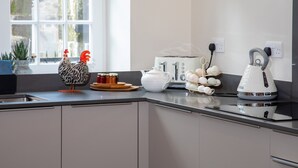 Una cocina moderna con ventana, un tostador, una tetera y un gallo decorativo.