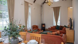 Un salón acogedor con chimenea, asientos cómodos y un comedor con un jarrón de flores.