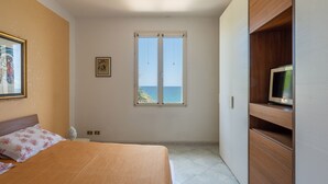 A bedroom with a bed, a television on a wooden cabinet, a window with a view of the sea, and a framed picture on the wall. - Villetta Ficarazzi by Wonderful Italy (Ficarazzi)