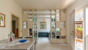 A spacious living area with a dining table, chairs, a sofa, and built-in shelving with various decorative items. - Villetta Ficarazzi by Wonderful Italy (Ficarazzi)
