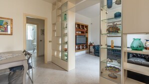 A modern living room with a dining area, featuring glass-fronted shelves with decorative items and a television. - Villetta Ficarazzi by Wonderful Italy (Ficarazzi)