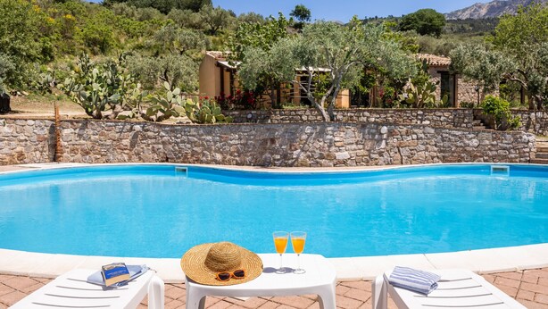 A swimming pool with lounge chairs and a table with drinks and a hat. - Villa Granci con Piscina by Wonderful Italy (Polizzi Generosa)