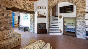 A rustic stone interior with a fireplace, a staircase, and a bed. - Villa Granci con Piscina by Wonderful Italy (Polizzi Generosa)