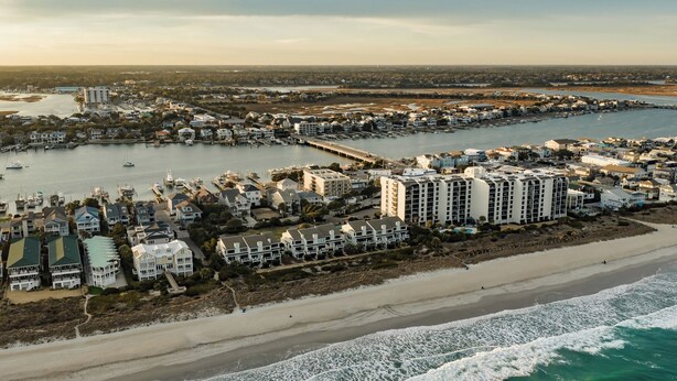 An aerial view of a coastal resort with beachfront properties, a marina, and a pier.