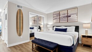 Ein modernes Schlafzimmer mit einem großen Bett, einer Bank, einem Spiegel und Bildern an der Wand.
