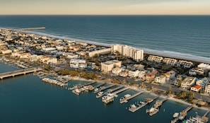 Vue aérienne d’une ville côtière avec un port de plaisance, des immeubles résidentiels et une jetée qui s’avance dans l’océan.