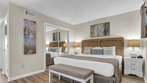 Ein Schlafzimmer mit einem großen Bett, Nachttischen, einer Bank und Bildern an den Wänden.