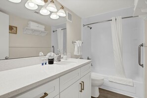 Une salle de bain moderne avec un lavabo blanc, un meuble-lavabo et un espace douche.