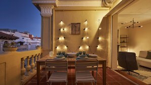 Una terraza con mesa lista para comer, una silla y un sofá.