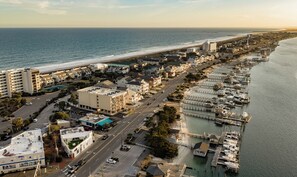 An aerial view of a coastal town with a marina, beachfront, and residential buildings.