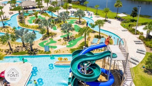 A water park with multiple slides and pools, surrounded by palm trees and a body of water.