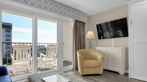 Una habitación de hotel con balcón, televisión, escritorio y silla.