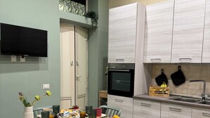 Moderni keittiö, jossa on valkoiset kaapit, sisäänrakennettu uuni ja ruokailutila, jossa on aamiaiselle katettu pöytä.