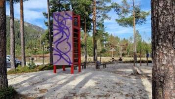 A concrete structure with graffiti, surrounded by trees and a clear sky.