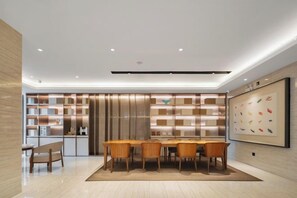 A modern dining area with a wooden table and chairs, a kitchen area with built-in shelves, and a framed picture on the wall. - JI Hotel (Xiamen SM Square Chenggong Avenue) (Xiamen)