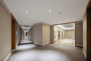 A hotel corridor with a patterned floor, a ceiling with recessed lighting, and a glass door leading to a room. - JI Hotel (Xiamen SM Square Chenggong Avenue) (Xiamen)