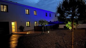 A modern building with a flat roof and multiple windows, surrounded by a gravel courtyard.