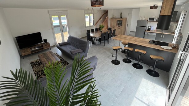 A modern apartment with a living room, dining area, kitchen, and a staircase.