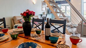 A dining area with a wooden table set for four, a vase with flowers, and a staircase leading to an upper level. - 3 Bed in Kingswear (oc-a29168) (Dartmouth)