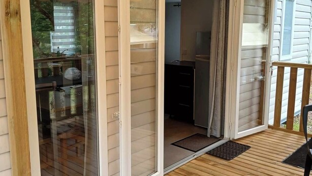 Een houten terras met een schuifdeur naar een keuken.